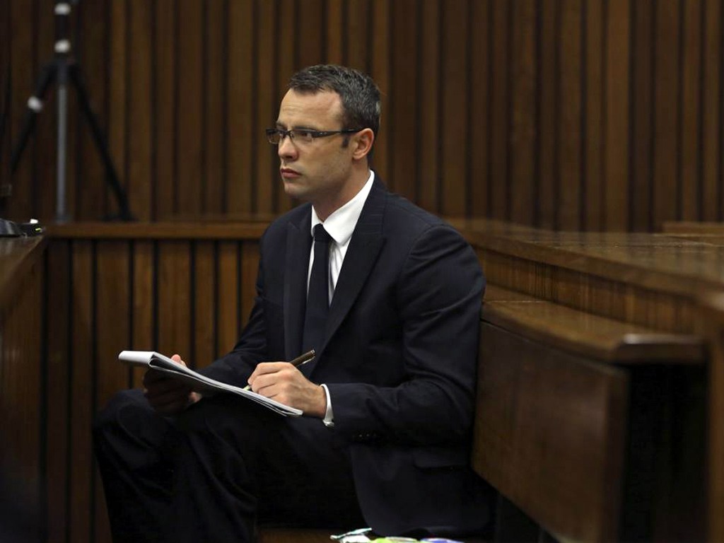 Olympic and Paralympic track star Oscar Pistorius takes notes during court proceedings at the North Gauteng High Court in Pretoria March 13, 2014.