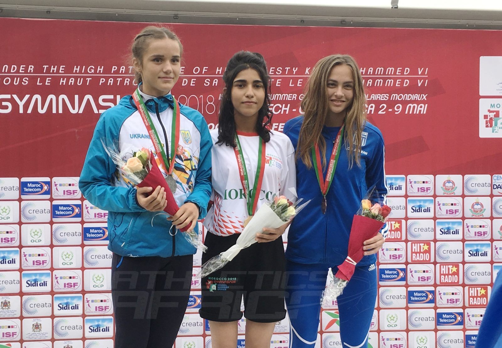 Morocco's Chaimae Arrouf (C) flanked by Svitlana Zhulzhyk of Ukraine and Ioanna Panapoulou of Greece on the podium after the Girls 800m medal presentation at Gymnasiade 2018 in Marrakech / Photo Credit: Yomi Omogbeja